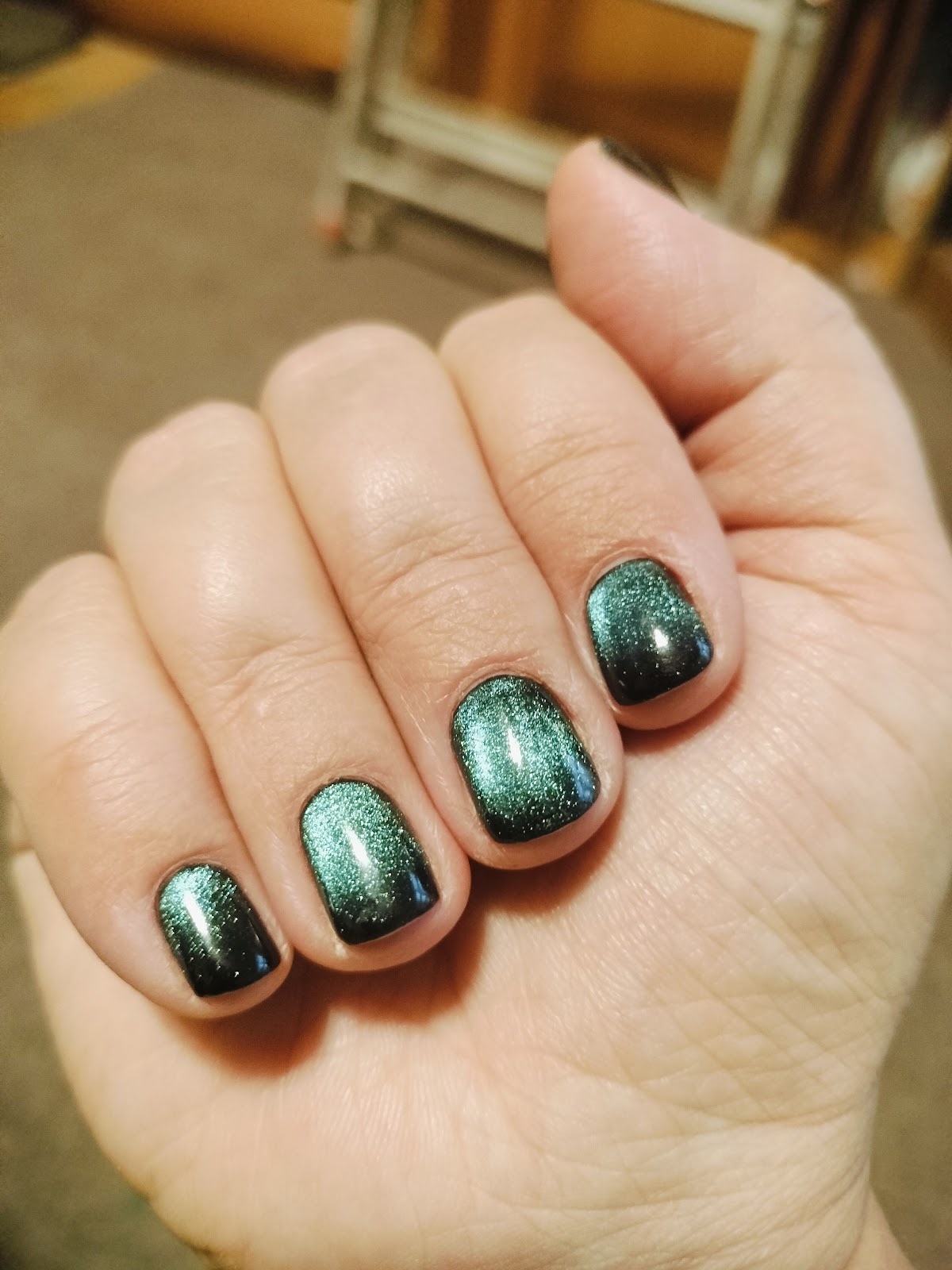 Manicure hybrydowy w kolorze szmaragdowym z efektem kociego oka