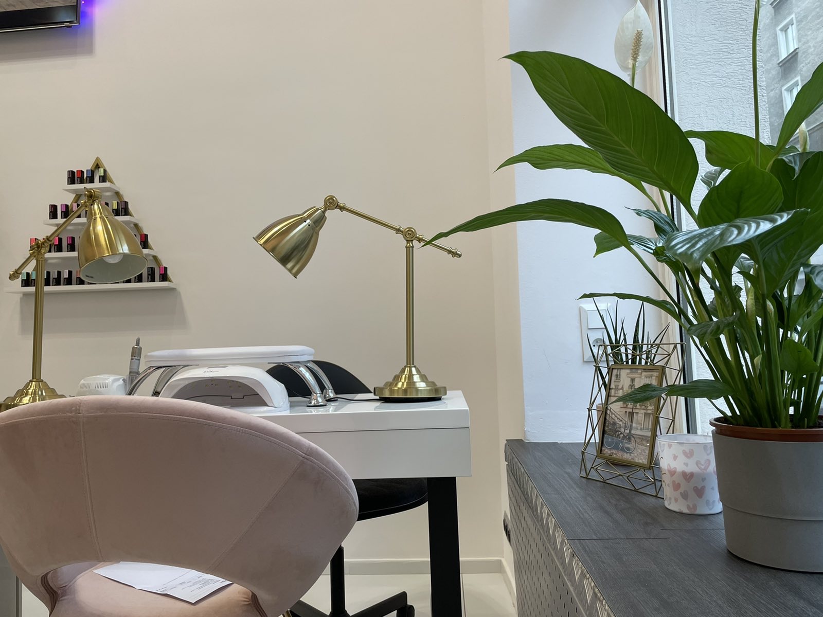 Stanowisko manicure ze zlota lampa i roslina przy oknie
